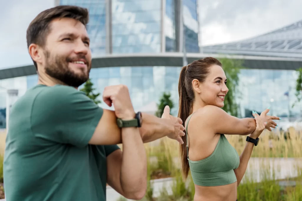 athletic man and woman stretching arms outside in utc